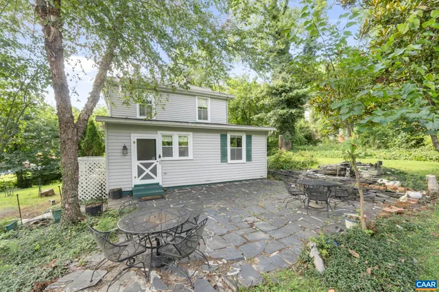 a view of a backyard with table and chairs potted plants and large tree