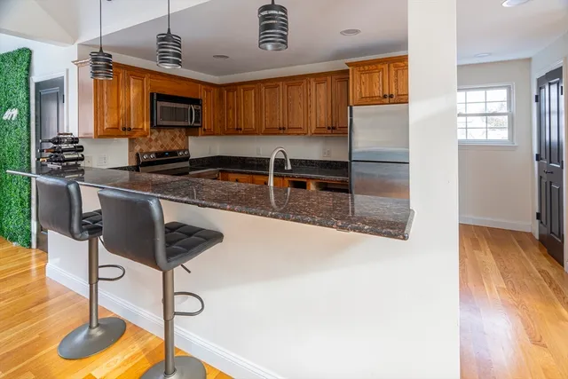 a kitchen with stainless steel appliances granite countertop a sink a stove and a wooden floors