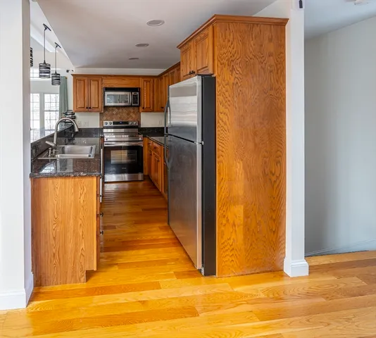 a kitchen with stainless steel appliances granite countertop a refrigerator a stove and a sink