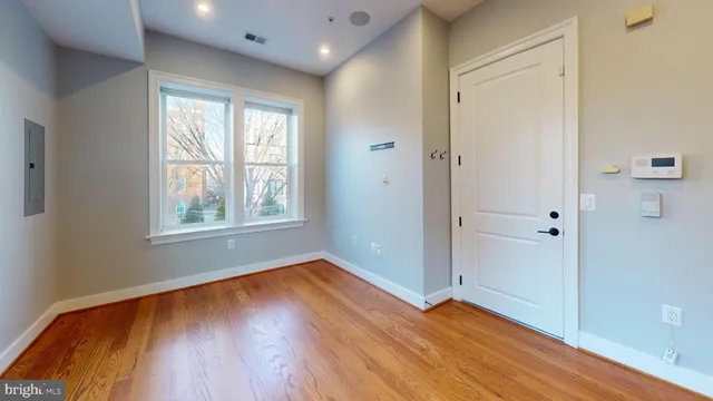 an empty room with wooden floor and windows