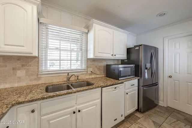 a kitchen with granite countertop a sink stainless steel appliances and cabinets