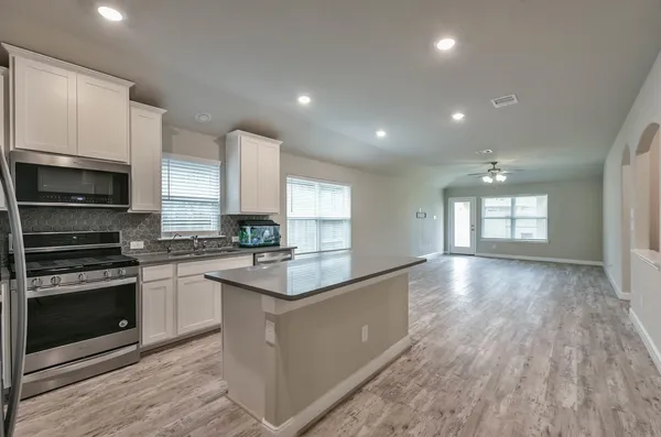 a kitchen with stainless steel appliances granite countertop a stove a sink and a microwave