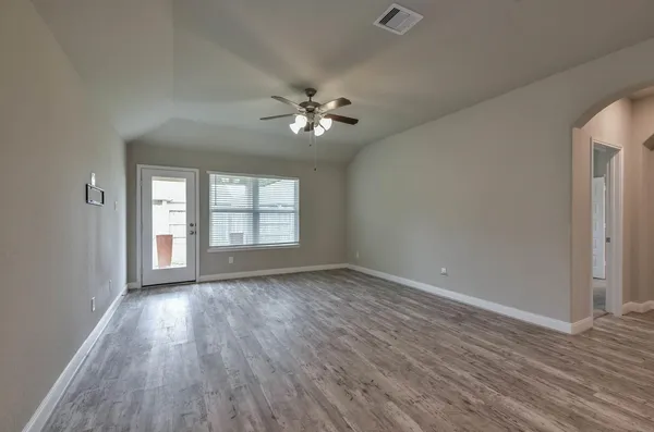 a view of empty room with wooden floor and fan
