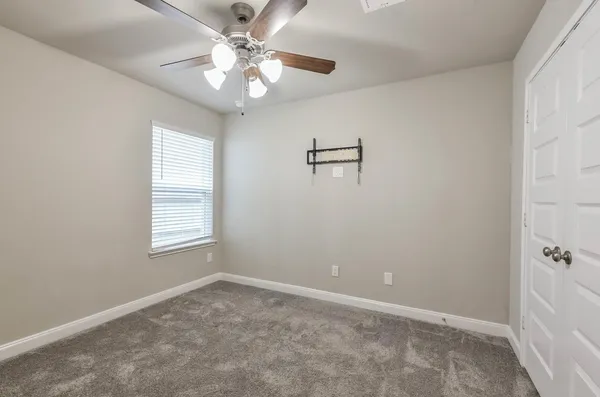 an empty room with windows and fan