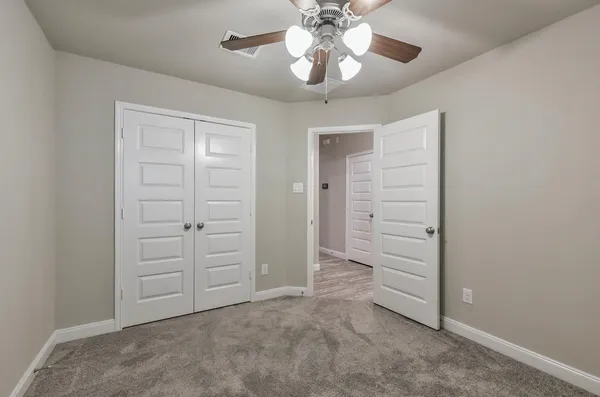an empty room with closet and a ceiling fan