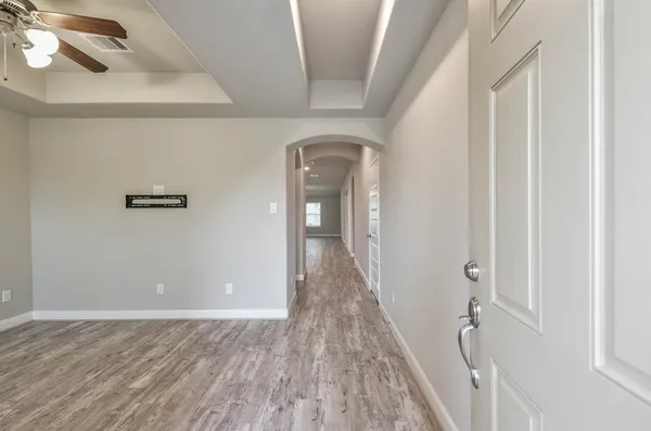 a view of a hallway with wooden floor and a bathroom