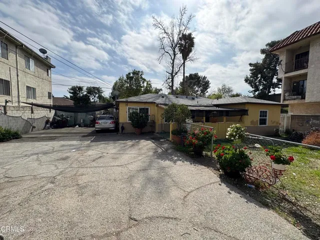 a view of house with yard outdoor seating and covered with trees