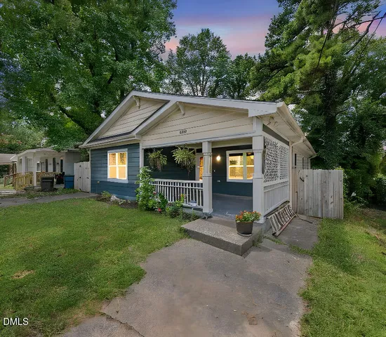 a view of a house with a small yard plants and large tree