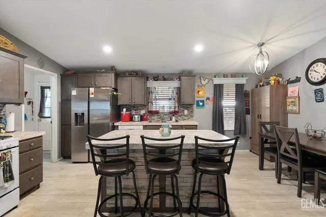 a dining area with stainless steel appliances kitchen island granite countertop a dining table chairs and refrigerator