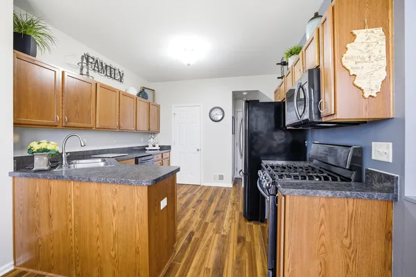 a kitchen with granite countertop a stove a sink a refrigerator and wooden cabinets