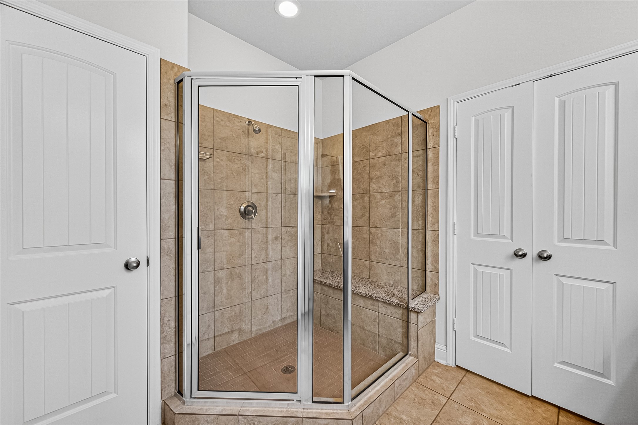 8107 Lockridge Terrace Lane Cypress, TX 77433 - Photo 34 of 50 Step into the luxurious walk-in shower framed by elegant glass and warm tile surround—perfectly situated between dual closets for ultimate convenience and function in the primary suite.