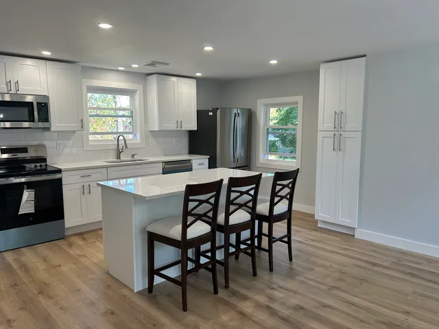 a kitchen with stainless steel appliances granite countertop wooden floor dining table and chairs