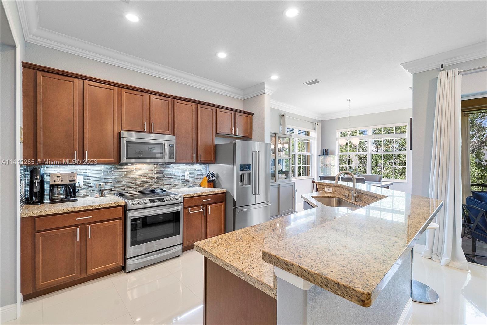 Heron Bay Parkland, FL 33076 - Photo 16 of 60 a kitchen with stainless steel appliances granite countertop a stove top oven a sink dishwasher a dining table and chairs with wooden floor