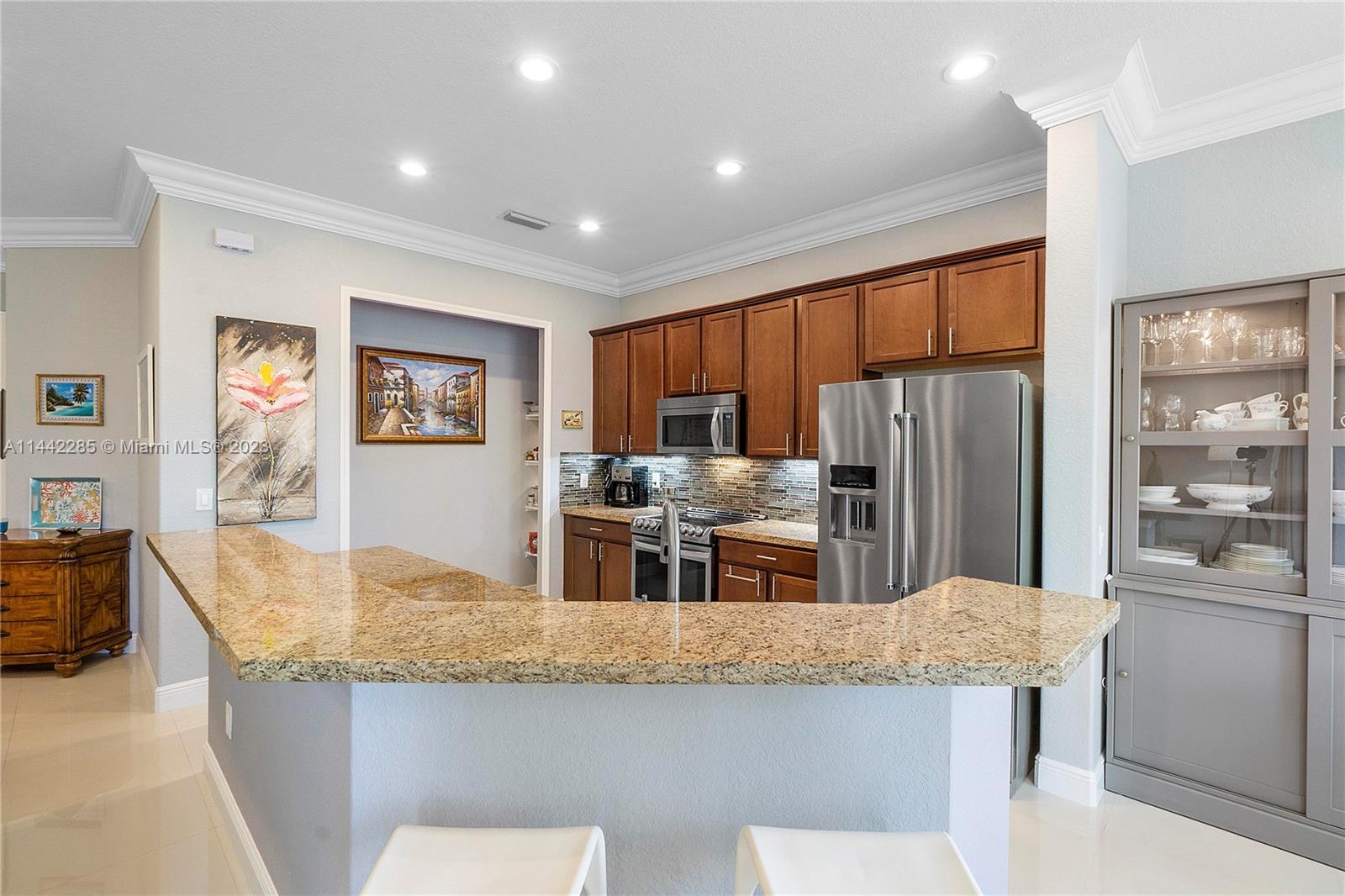 Heron Bay Parkland, FL 33076 - Photo 18 of 60 a kitchen with stainless steel appliances granite countertop a refrigerator a stove top oven a sink a dining table and chairs with wooden floor