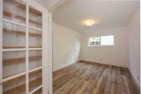 a view of an empty room with a window and wooden floor