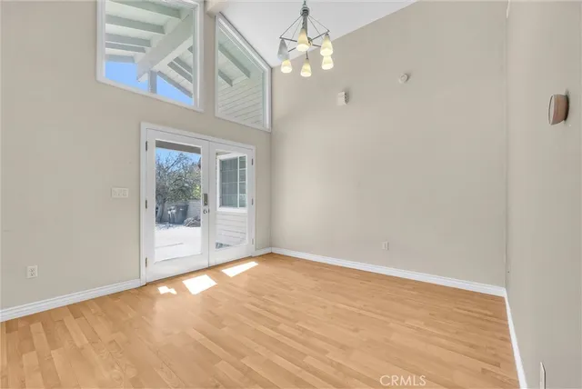 an empty room with chandelier fan and windows