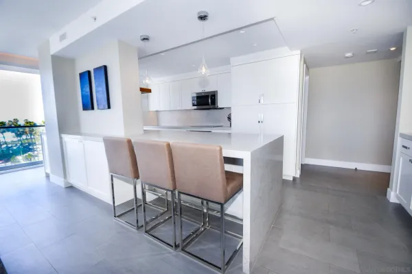 a kitchen with stainless steel appliances granite countertop a stove a sink a refrigerator and a dining table with wooden floor