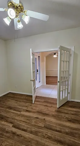 a view of an empty room with wooden floor and window
