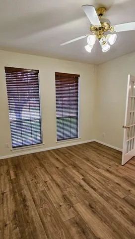 a view of an empty room with window and chandelier fan