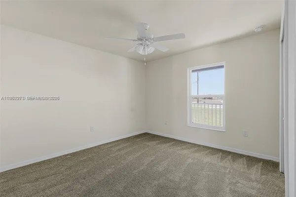 an empty room with a window and a fan