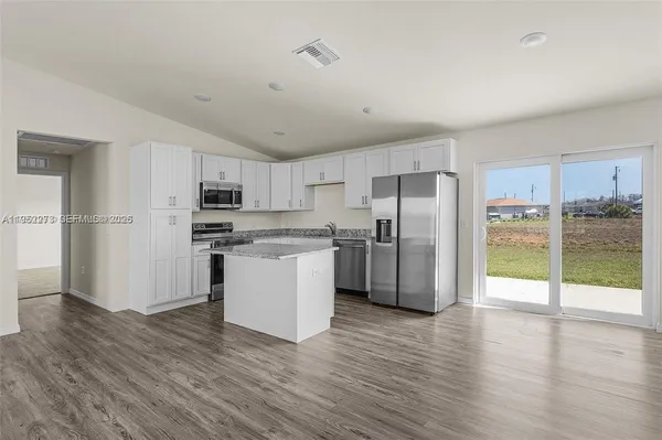 a kitchen with stainless steel appliances a refrigerator and wooden floor