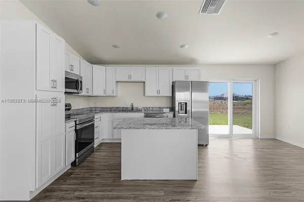 a kitchen with stainless steel appliances granite countertop a stove top oven a sink and a refrigerator