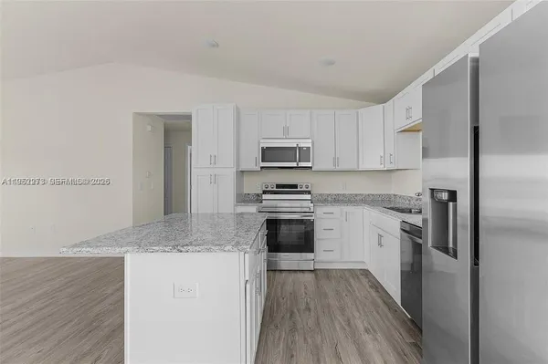 a kitchen with granite countertop white cabinets and stainless steel appliances