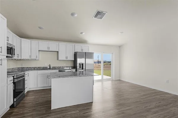 a large kitchen with cabinets wooden floor and stainless steel appliances