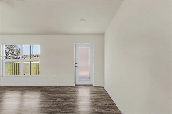 a view of a livingroom with wooden floor and a kitchen