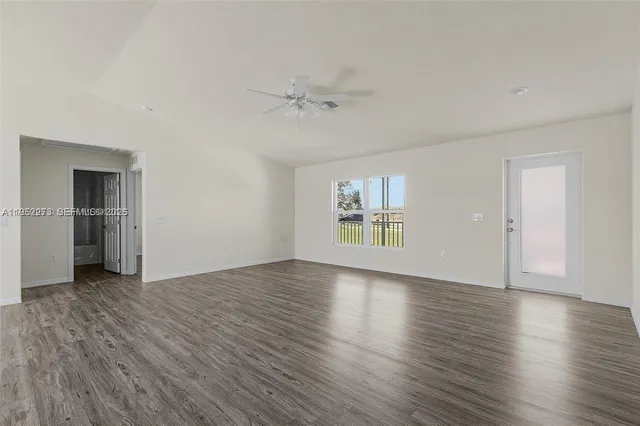 an empty room with wooden floor cabinet and windows