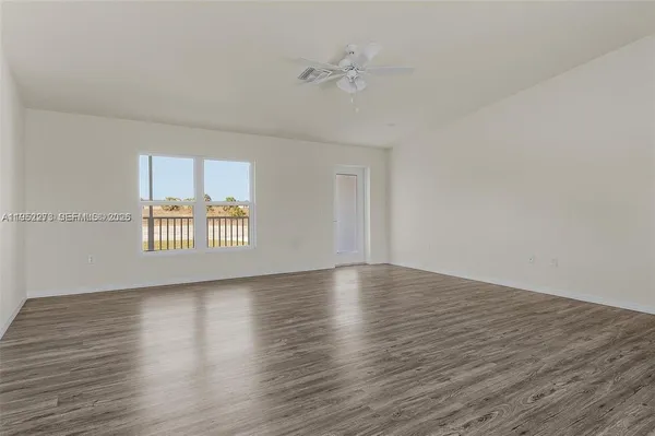 a view of an empty room with a window and wooden floor