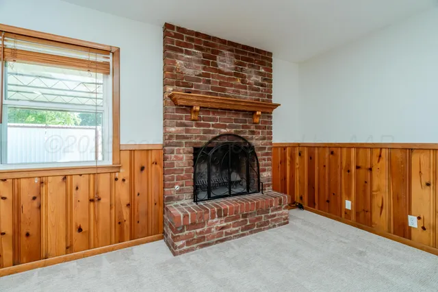a view of a livingroom with a fireplace a ceiling fan and windows