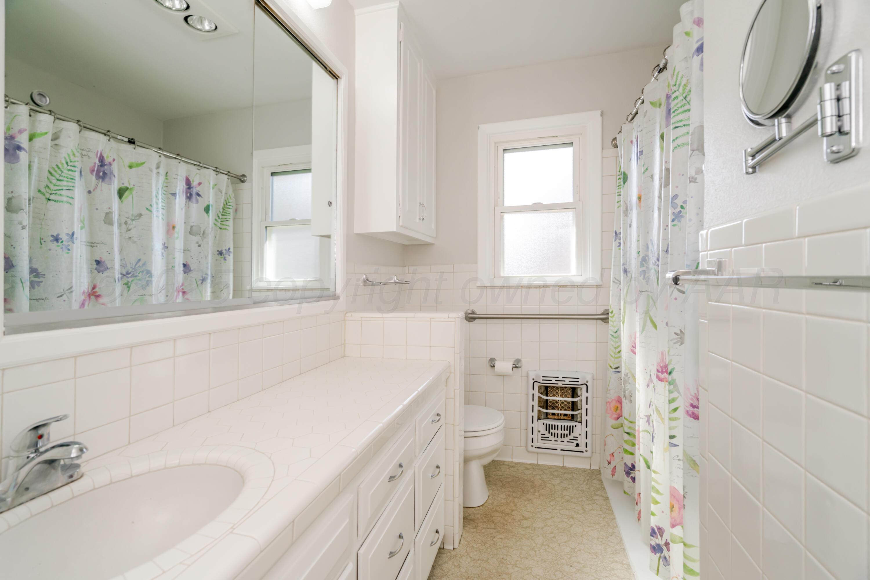 4721 Cherokee Trail Amarillo, TX 79109 - Photo 26 of 42 a bathroom with a granite countertop sink a mirror and a bathtub