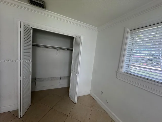 a view of an empty room with closet and a window