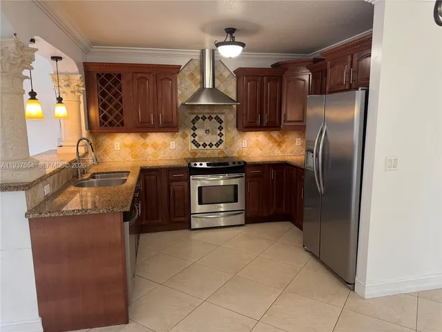 a kitchen with stainless steel appliances granite countertop a refrigerator a stove and a sink