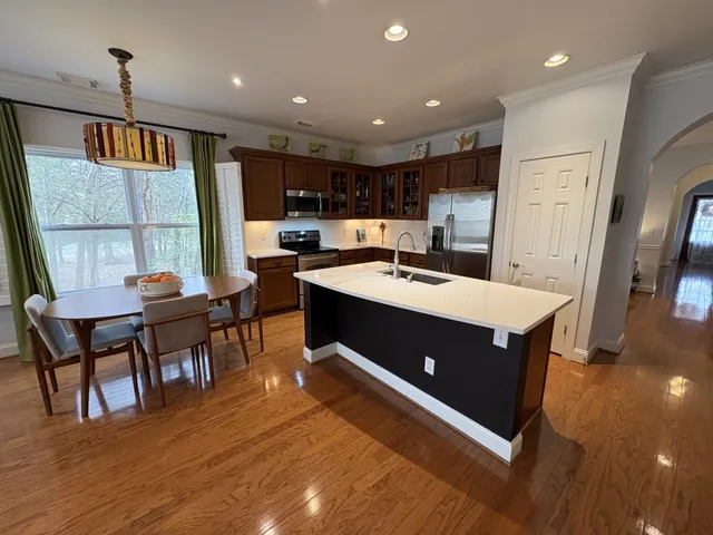 a kitchen with stainless steel appliances kitchen island granite countertop a table chairs and a refrigerator