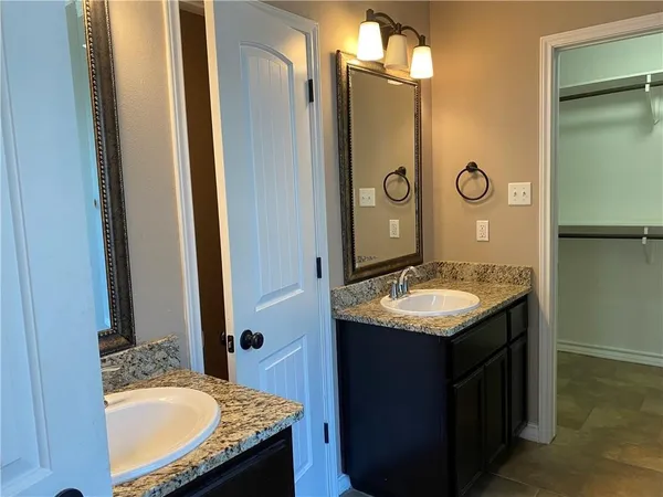 a bathroom with a granite countertop sink a mirror and a shower
