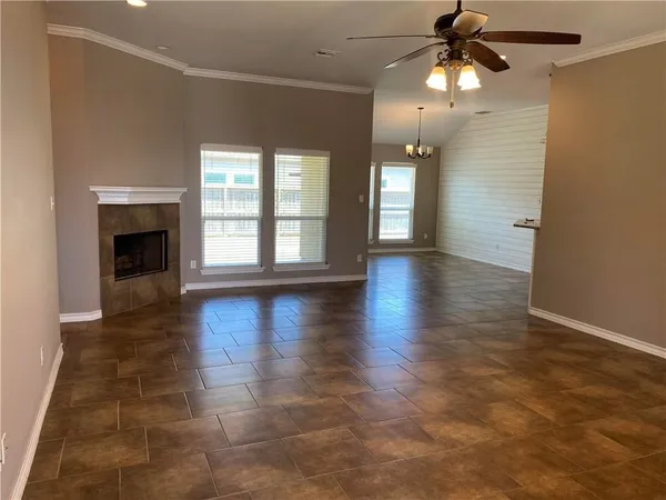 an empty room with wooden floor chandelier and windows
