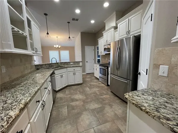 a large kitchen with stainless steel appliances granite countertop a sink stove and refrigerator