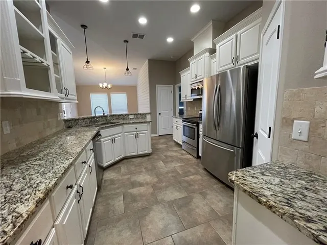 a large kitchen with stainless steel appliances granite countertop a sink stove and refrigerator