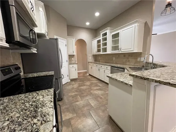 a kitchen with stainless steel appliances granite countertop a refrigerator and a stove top oven