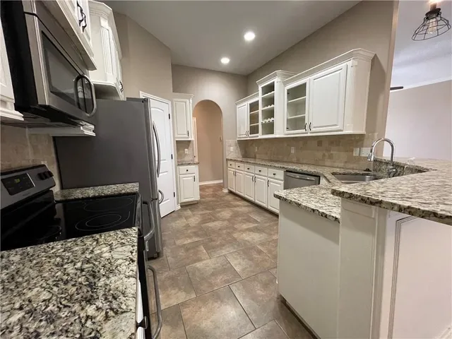 a kitchen with stainless steel appliances granite countertop a refrigerator and a stove top oven