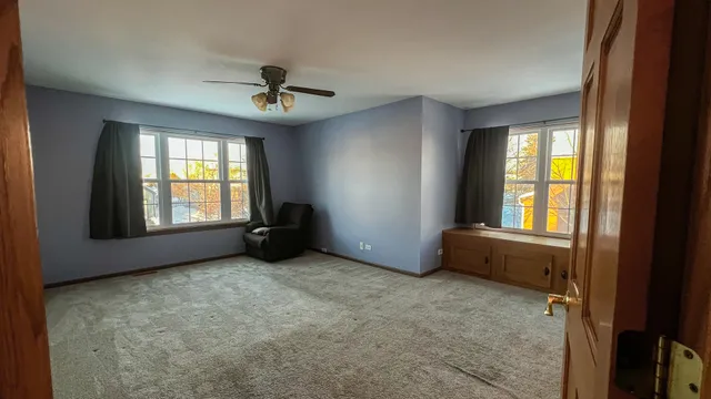 an empty room with windows and ceiling fan