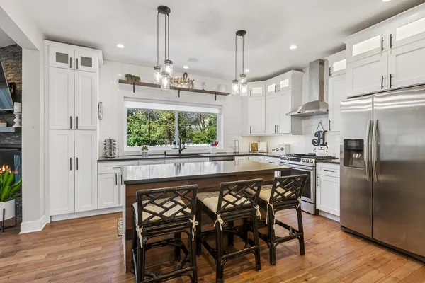 a kitchen with stainless steel appliances granite countertop a table chairs stove and wooden floor