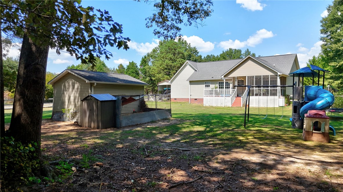 247 Clardy Road Pelzer, SC 29669 - Photo 2 of 34 Mature trees shade a spacious green lawn featuring a detached outbuilding and screened rear porch.