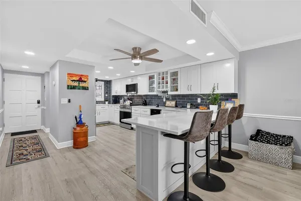 a open kitchen with stainless steel appliances granite countertop a stove top oven a refrigerator a sink and a dining table with wooden floor