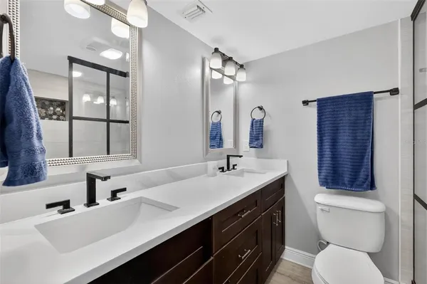 a bathroom with a double vanity sink toilet and mirror