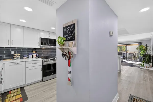 a kitchen with a refrigerator a stove top oven a sink dishwasher and white cabinets with wooden floor