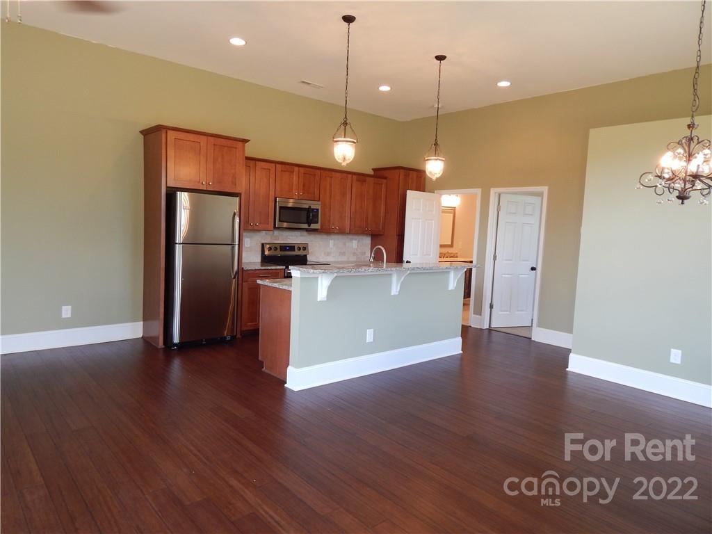 5312 Davis Road, Unit A Waxhaw, NC 28173 - Photo 7 of 12 a view of a kitchen with a refrigerator wooden floor and a kitchen