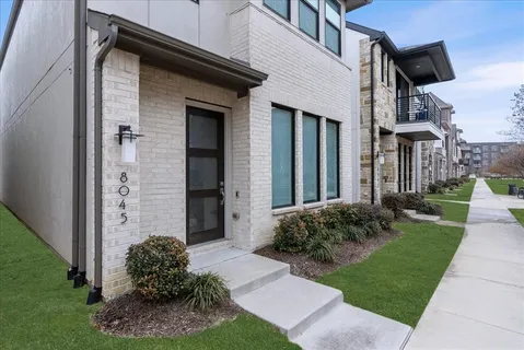 a view of a house with brick walls and a yard with plants